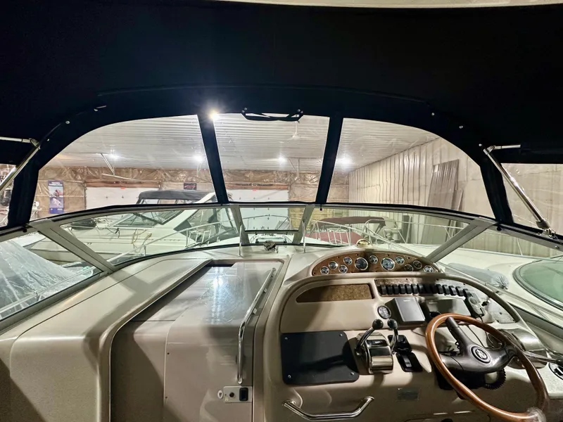 Slide: The Image of 1999 Sea Ray 310 Sundancer cockpit with steering wheel and control panel in a storage facility. - 13