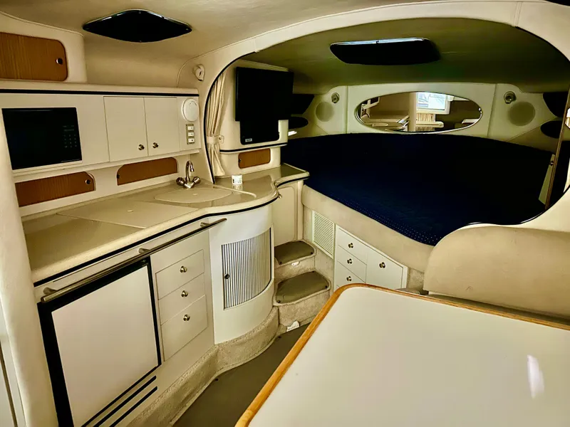 Slide: The Image of 1999 Sea Ray 310 Sundancer cabin interior with kitchenette and sleeping area. - 16