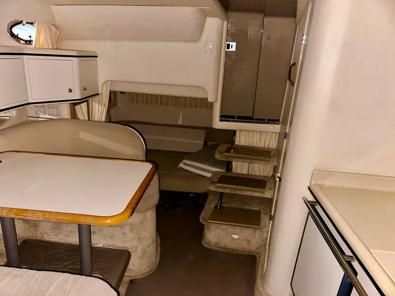 Slide: The Image of 1999 Sea Ray 310 Sundancer cabin interior with dining area and compact kitchenette. - 20