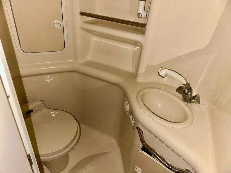 Slide: The Image of 1999 Sea Ray 310 Sundancer bathroom with toilet, sink, and storage shelves. - 21