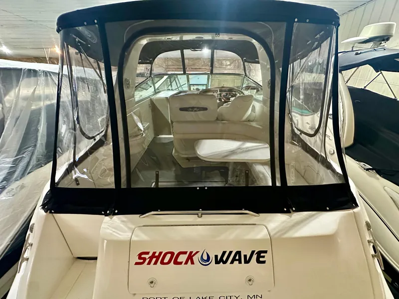 Slide: The Image of 1999 Sea Ray 310 Sundancer boat with "Shock Wave" branding, docked indoors. - 5