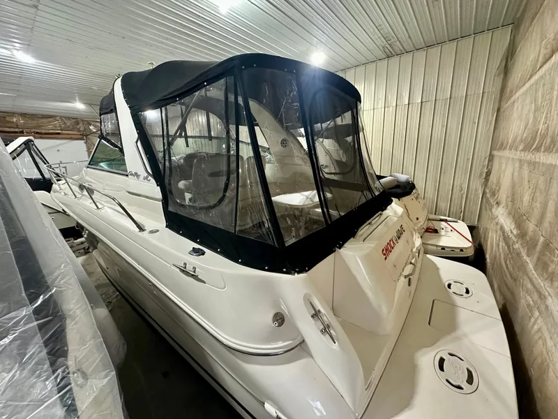Slide: The Image of 1999 Sea Ray 310 Sundancer boat in indoor storage with black canopy. - 6