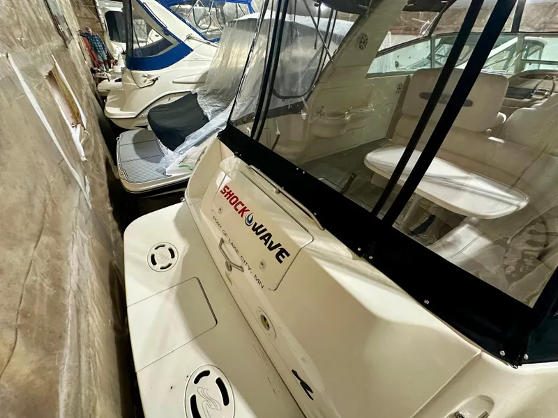 Slide: The Image of 1999 Sea Ray 310 Sundancer boat docked indoors, featuring spacious seating and covered deck. - 7