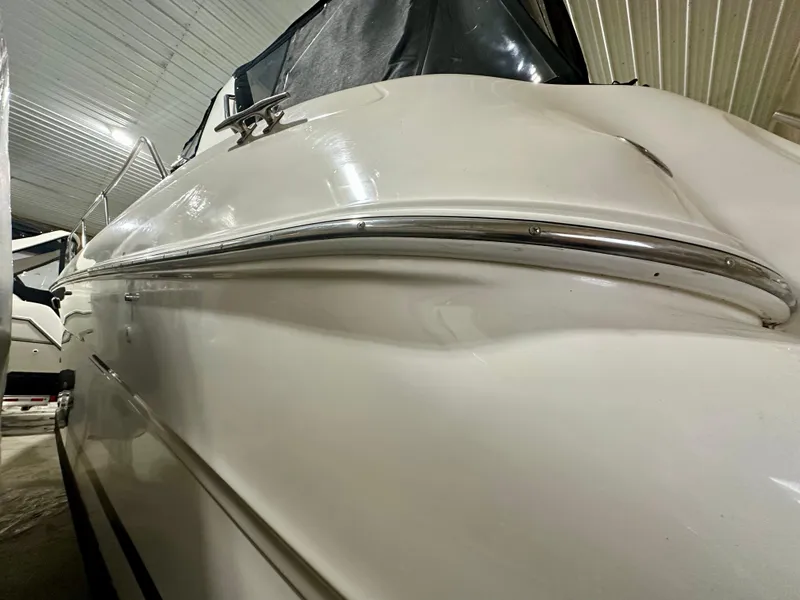 Slide: The Image of 1999 Sea Ray 310 Sundancer boat in indoor storage, showcasing sleek white exterior. - 8
