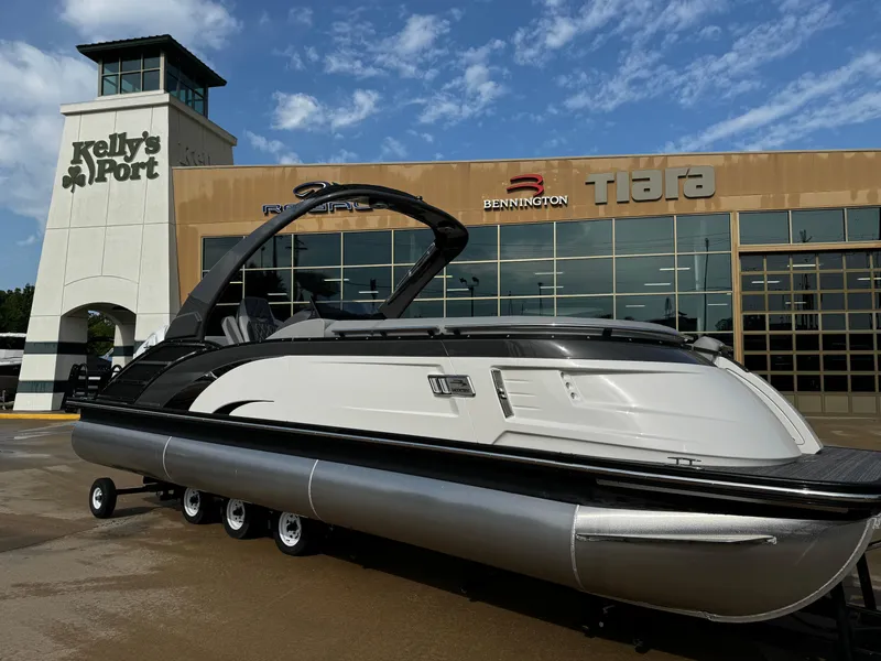Slide: The Image of 2024 Bennington 25 QXSBA pontoon boat displayed at dealership under blue sky. - 1