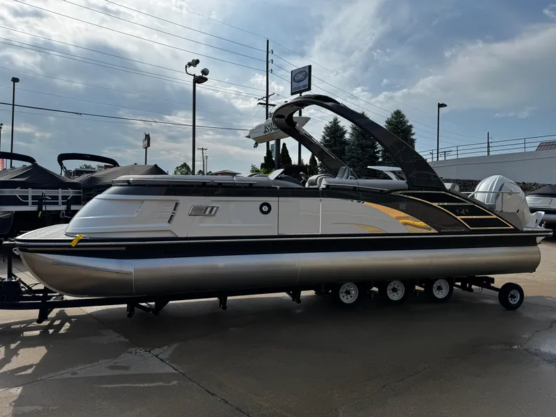 Slide: The Image of 2024 Bennington 25 QXSBA pontoon boat on trailer, parked outdoors. - 6