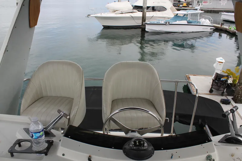 Slide: The Image of 1985 Trojan 10m Fly bridge with dual seats and steering wheel, docked near other boats. - 12