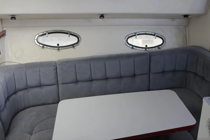Slide: The Image of Interior of a 1985 Trojan 10m Fly yacht with gray seating and oval windows. - 23