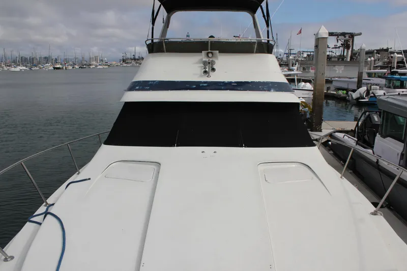 Slide: The Image of 1985 Trojan 10m Fly yacht docked at marina, showcasing sleek design and spacious deck. - 4