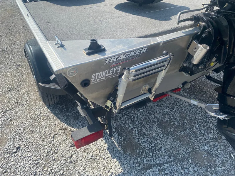 Slide: The Image of 2019 Bass Tracker Classic boat trailer with visible branding and ladder on gravel surface. - 7