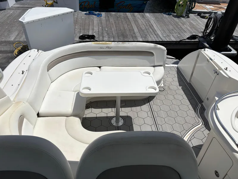 Slide: The Image of 2003 Sea Ray 340 Sundancer boat interior with white seating and table on a hexagonal-patterned deck. - 6