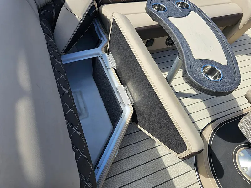 Slide: The Image of 2024 SunCatcher Elite 326 SE boat interior with open storage compartment and cup holders. - 20