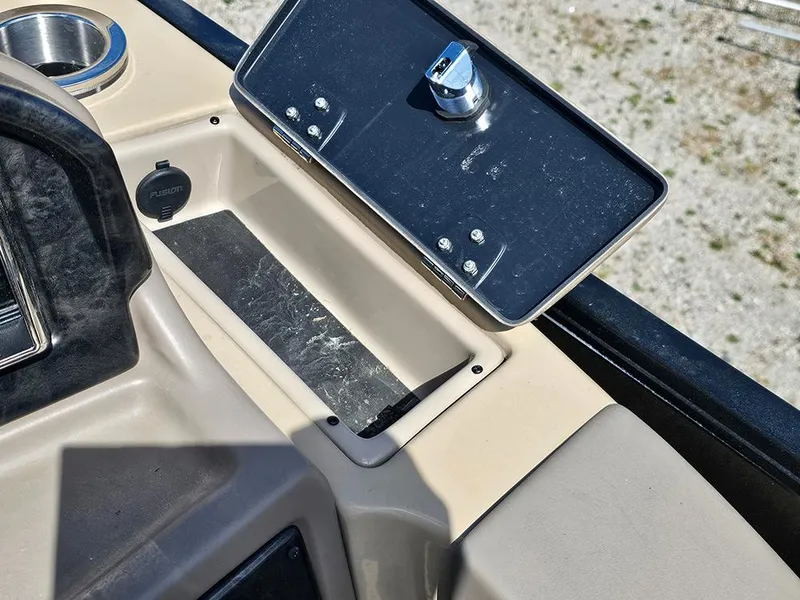 Slide: The Image of 2024 SunCatcher Elite 326 SE dashboard with open storage compartment and cup holder. - 28