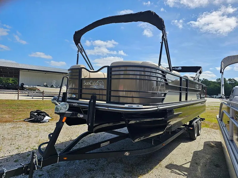 Slide: The Image of 2024 SunCatcher Elite 326 SE pontoon boat on trailer, parked outdoors under blue sky. - 5