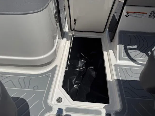 Slide: The Image of 2025 Regal LS6 Surf boat storage compartment with open hatch and gray flooring. - 17