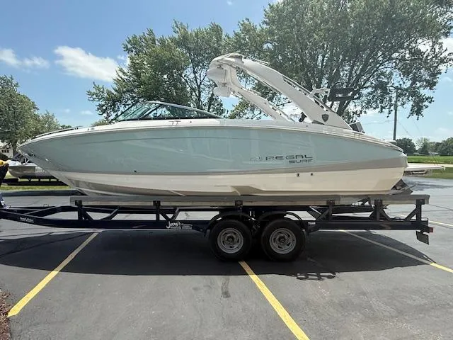 Slide: The Image of 2025 Regal LS6 Surf boat on trailer, parked outdoors, sunny day. - 2