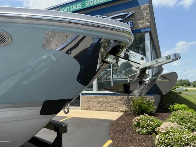 Slide: The Image of 2025 Regal LS6 Surf boat bow with anchor, outside a boat sales store. - 4