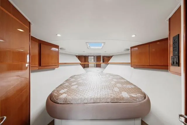 Slide: The Image of 1998 Viking 43 Open yacht interior with bed, wooden cabinets, and skylight. - 48