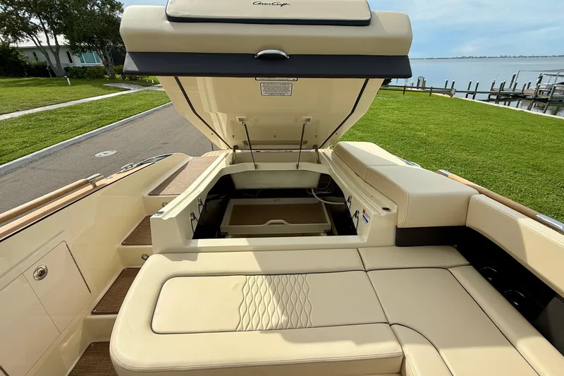 Slide: The Image of 2026 Chris-Craft Sportster 28 boat interior with open engine compartment, beige seating, and waterfront view. - 13