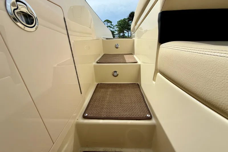 Slide: The Image of Steps on a 2026 Chris-Craft Sportster 28 boat, featuring beige upholstery and brown mats. - 16