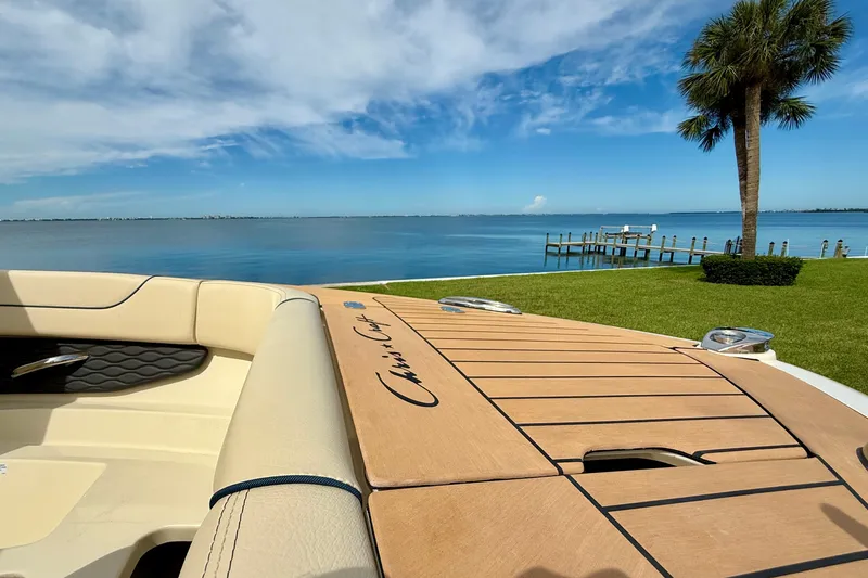Slide: The Image of 2026 Chris-Craft Sportster 28 boat by a serene lake with palm tree and dock. - 30