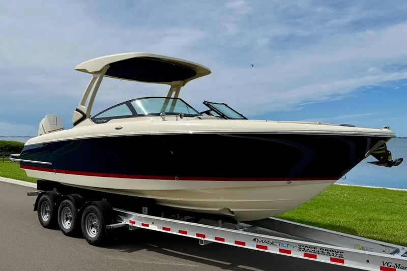 Slide: The Image of 2026 Chris-Craft Sportster 28 boat on trailer, parked near a scenic waterfront. - 4