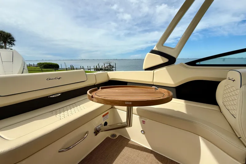 Slide: The Image of 2026 Chris-Craft Sportster 28 interior with elegant seating and wooden table, overlooking serene waters. - 43