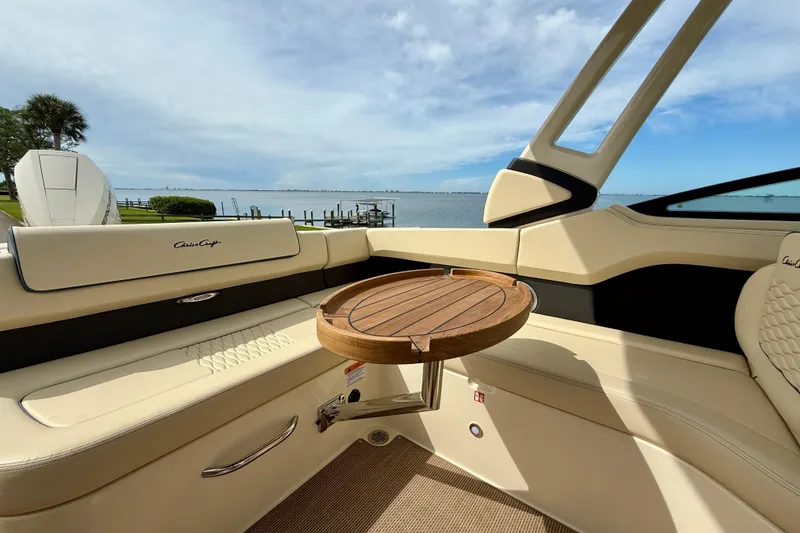 Slide: The Image of 2026 Chris-Craft Sportster 28 interior with elegant seating and wooden table, overlooking serene waters. - 44