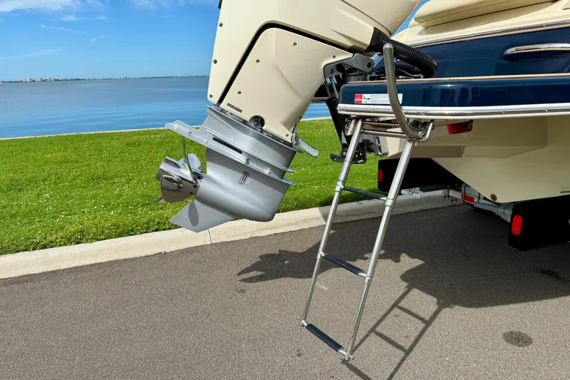 Slide: The Image of 2026 Chris-Craft Sportster 28 boat with outboard motor and ladder by a lakeside. - 48