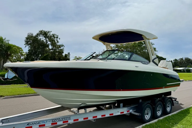 Slide: The Image of 2026 Chris-Craft Sportster 28 boat on trailer, parked on a street with trees in background. - 5