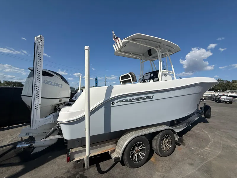 Slide: The Image of 2022 Aquasport 2300 Center Console boat on trailer under clear blue sky. - 25