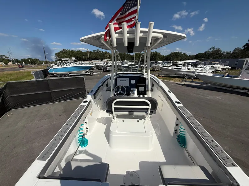 Slide: The Image of 2022 Aquasport 2300 Center Console boat with American flag, docked under clear blue sky. - 34