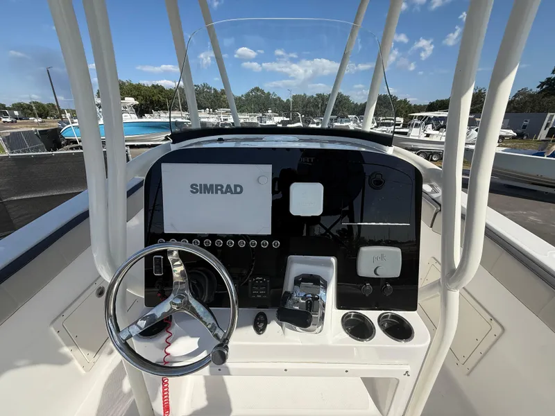 Slide: The Image of 2022 Aquasport 2300 Center Console boat dashboard with Simrad display and steering wheel. - 41