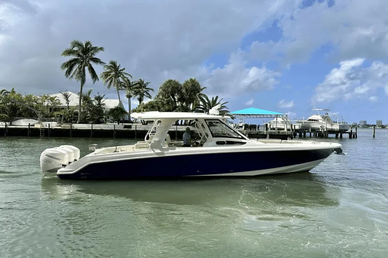 The Image of 2019 Boston Whaler 350 Realm boat on water, with palm trees and docks in the background. - 0