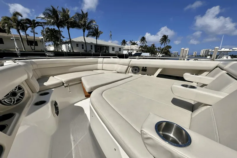 Slide: The Image of 2019 Boston Whaler 350 Realm boat interior with beige seating and cup holders, under a clear blue sky. - 14