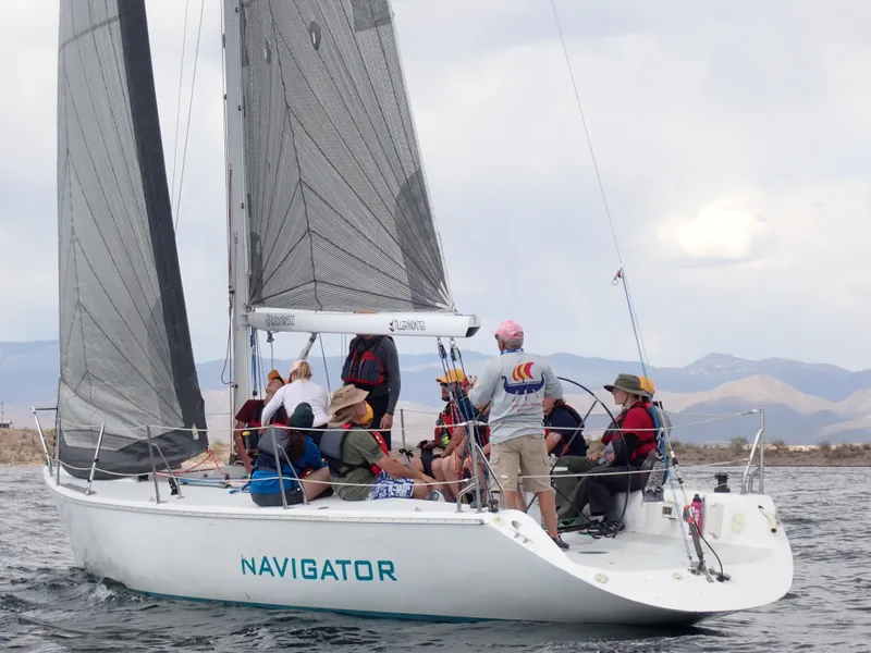 The Image of Sailboat Catalina Capri 37, 1992, with crew sailing on calm waters, mountains in background. - 0