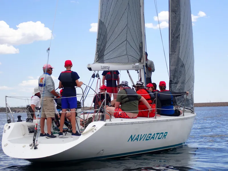 Slide: The Image of Sailors on a 1992 Catalina Capri 37 yacht named "Navigator" on calm waters. - 12