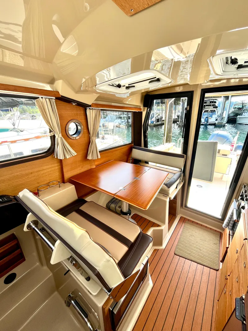 Slide: The Image of 2018 Ranger Tugs R-27 interior with wood accents, dining area, and large windows. - 10
