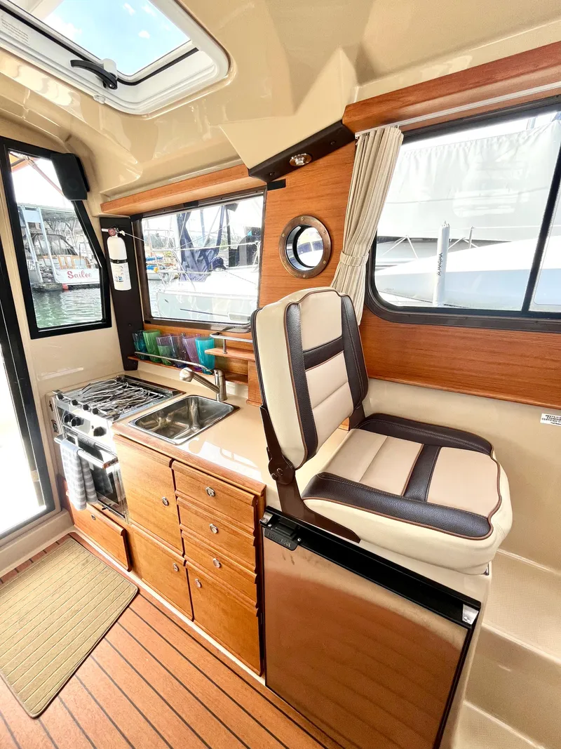 Slide: The Image of 2018 Ranger Tugs R-27 interior with kitchenette, seating, and wood accents. - 11