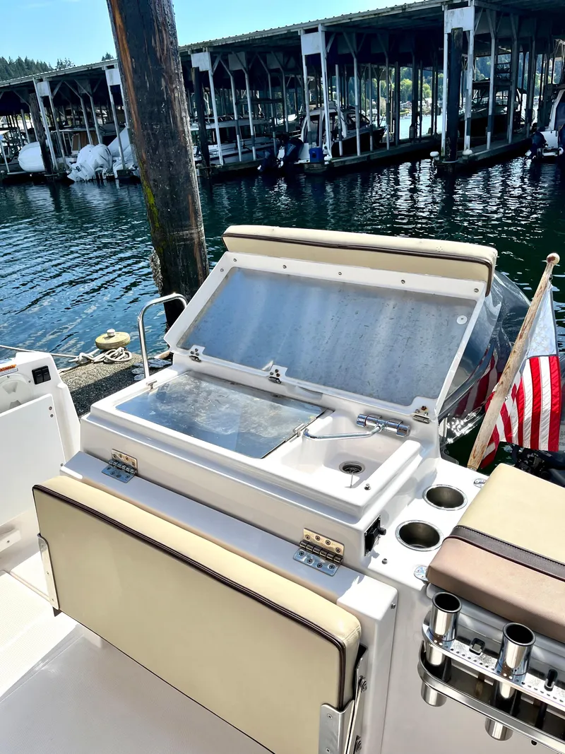 Slide: The Image of 2018 Ranger Tugs R-27 boat with open storage compartment, docked near marina. - 12