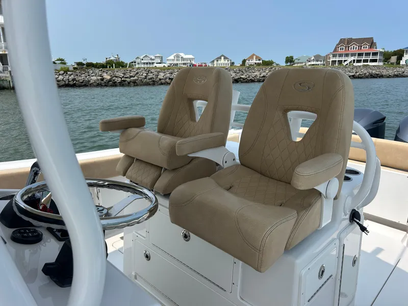 Slide: The Image of 2018 Sportsman Open 312 Center Console boat with tan captain seats, steering wheel, and waterfront view. - 15