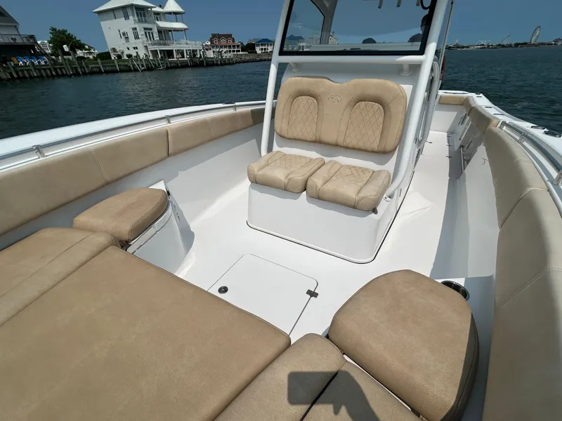 Slide: The Image of 2018 Sportsman Open 312 Center Console boat with beige seating, docked by waterfront homes. - 21