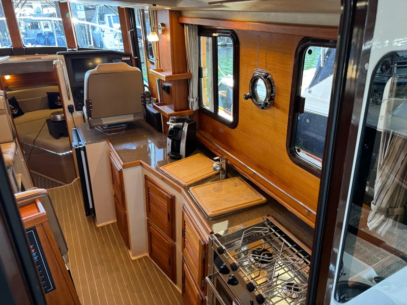Slide: The Image of 2020 Ranger Tugs R-31 S interior with wood finish, kitchen, and seating area. - 11