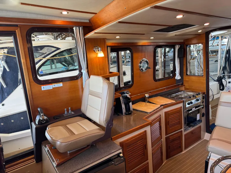 Slide: The Image of 2020 Ranger Tugs R-31 S interior with wood finish, seating, and kitchen area. - 16
