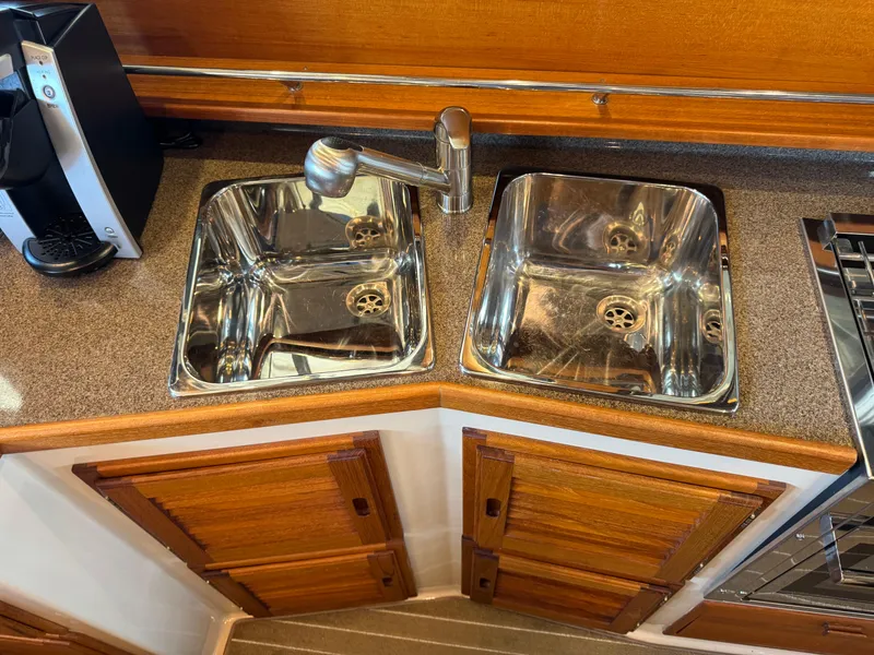 Slide: The Image of 2020 Ranger Tugs R-31 S kitchen sink area with dual stainless steel basins and wooden cabinetry. - 17