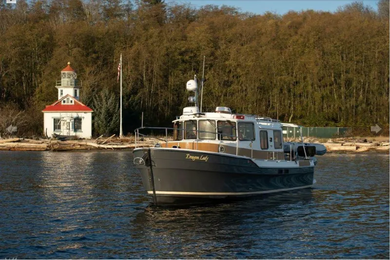 Slide: The Image of 2020 Ranger Tugs R-31 S boat cruising near a lighthouse on a sunny day. - 2