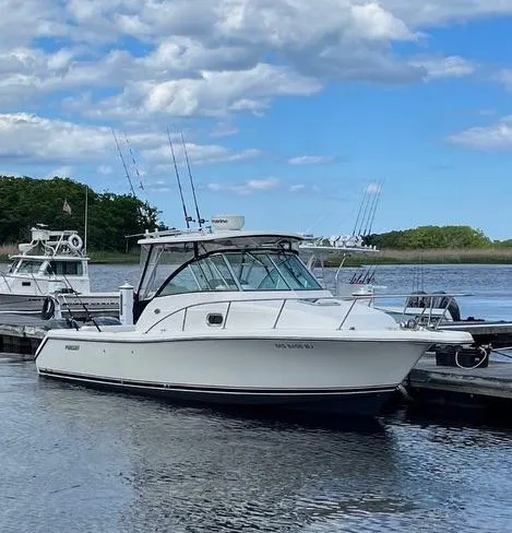 Slide: The Image of 2007 Pursuit 285 Offshore boat docked on a calm lake under a partly cloudy sky. - 0