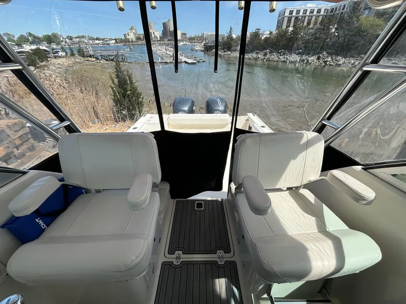 Slide: The Image of 2007 Pursuit 285 Offshore boat interior with two white seats, overlooking a scenic waterfront. - 11