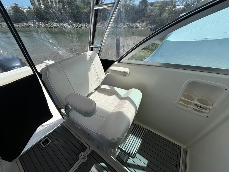 Slide: The Image of 2007 Pursuit 285 Offshore boat interior with cushioned seating and window view. - 15