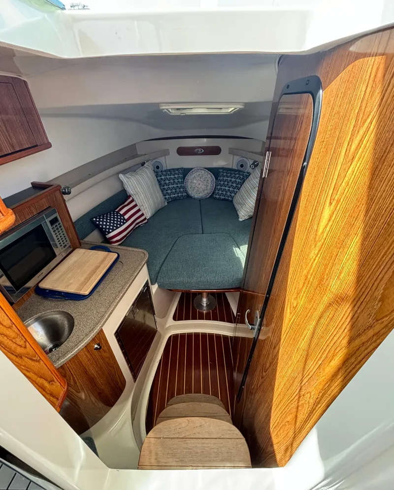 Slide: The Image of Interior of a 2007 Pursuit 285 Offshore boat with cozy seating and kitchenette. - 16